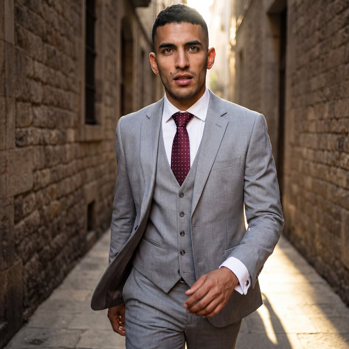 Hombre con traje gris y corbata de seda burdeos